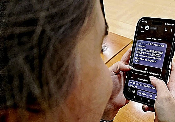 Una mujer lee en su móvil el mismo mensaje que recibió la denunciante en el que se le insta a confirmar sus datos para que no le bloqueen la tarjeta.