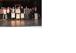 Foto de familia de los homenajeados y las autoridades en el teatro Cervantes