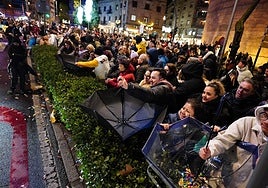 Un grupo de personas recogiendo caramelos con paraguas durante la cabalgata.