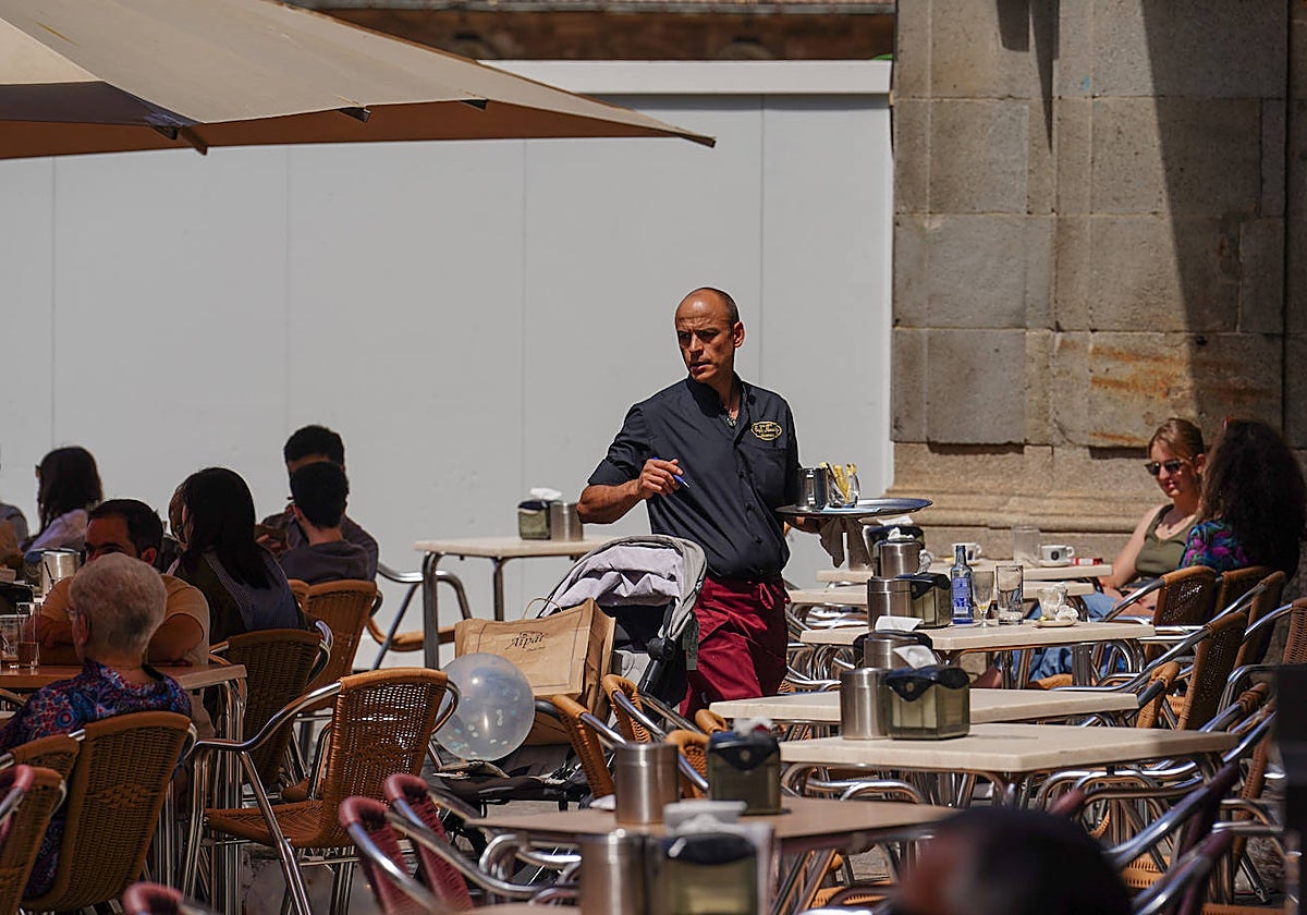 Un camarero atendiendo las mesas de una terraza.
