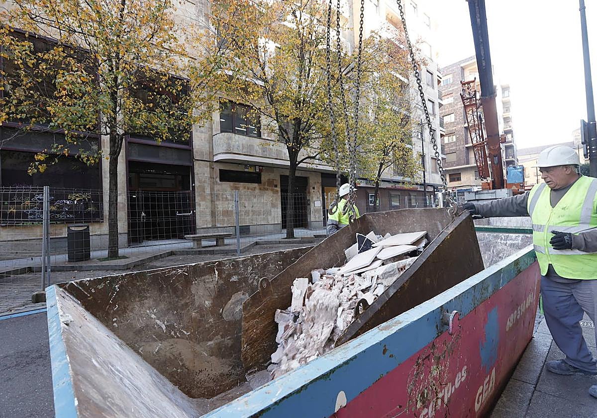 Un operario ayuda a depositar en un contenedor escombros procedentes de una obra.
