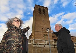 Dos vecinos muestran la torre de la iglesia de San Martín de Villaflores.