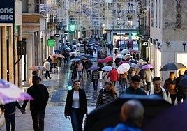 Salmantinos se refugian de la lluvia con paraguas en la tarde de este jueves.