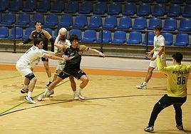 Álvaro Carretero intenta lanzar a puerta agarrado por dos rivales.