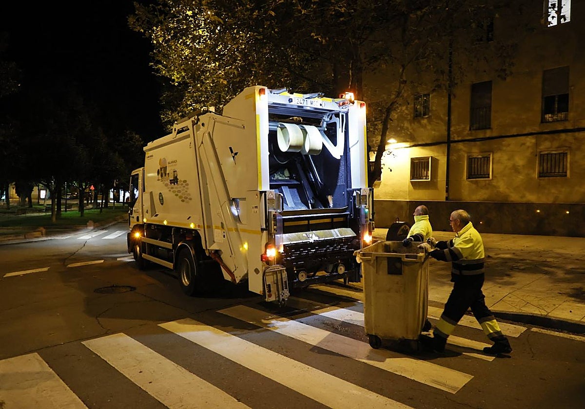 Dos trabajadores del servicio de recogida de basura, contenedores y camiones de recogida.
