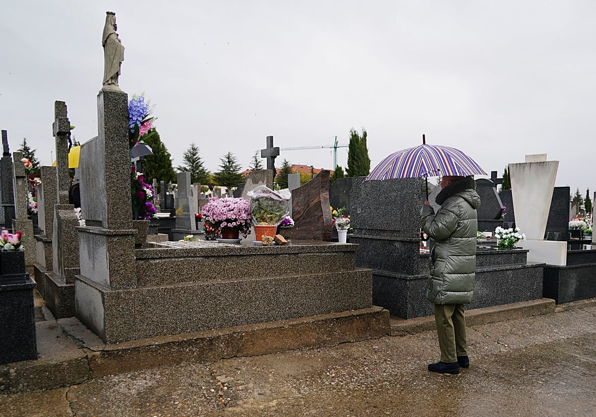 Una mujer vela a sus familiares con el paraguas por las lluvias del sábado.