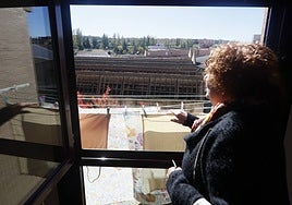Una vecina frente a su ventana desde la que se ve la antigua fábrica de lana abandonada.