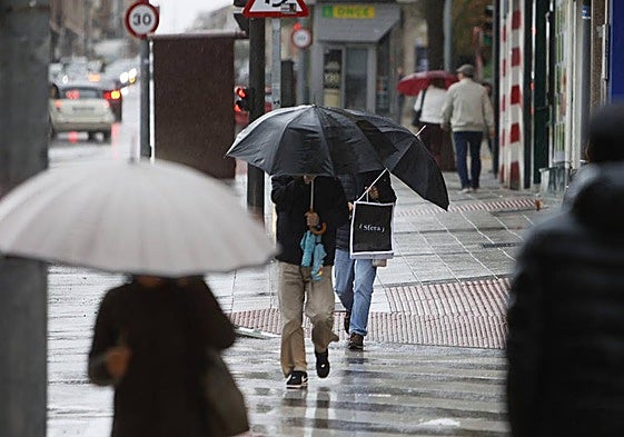 Un hombre se protege de la lluvia por las calles de Salamanca.