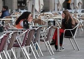 Dos jóvenes charlan en la mesa de una terraza del centro de Salamanca.