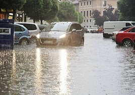 Un coche circula por una calle inundada en Valladolid.