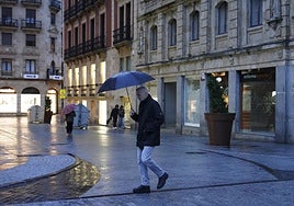 Un hombre se protege de la lluvia bajo un paraguas en pleno centro de Salamanca.