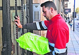 Un repartidor entra en el portal de un edificio de Salamanca para entregar un paquete.