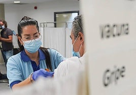 Una enfermera, vacunando a una persona de la gripe.