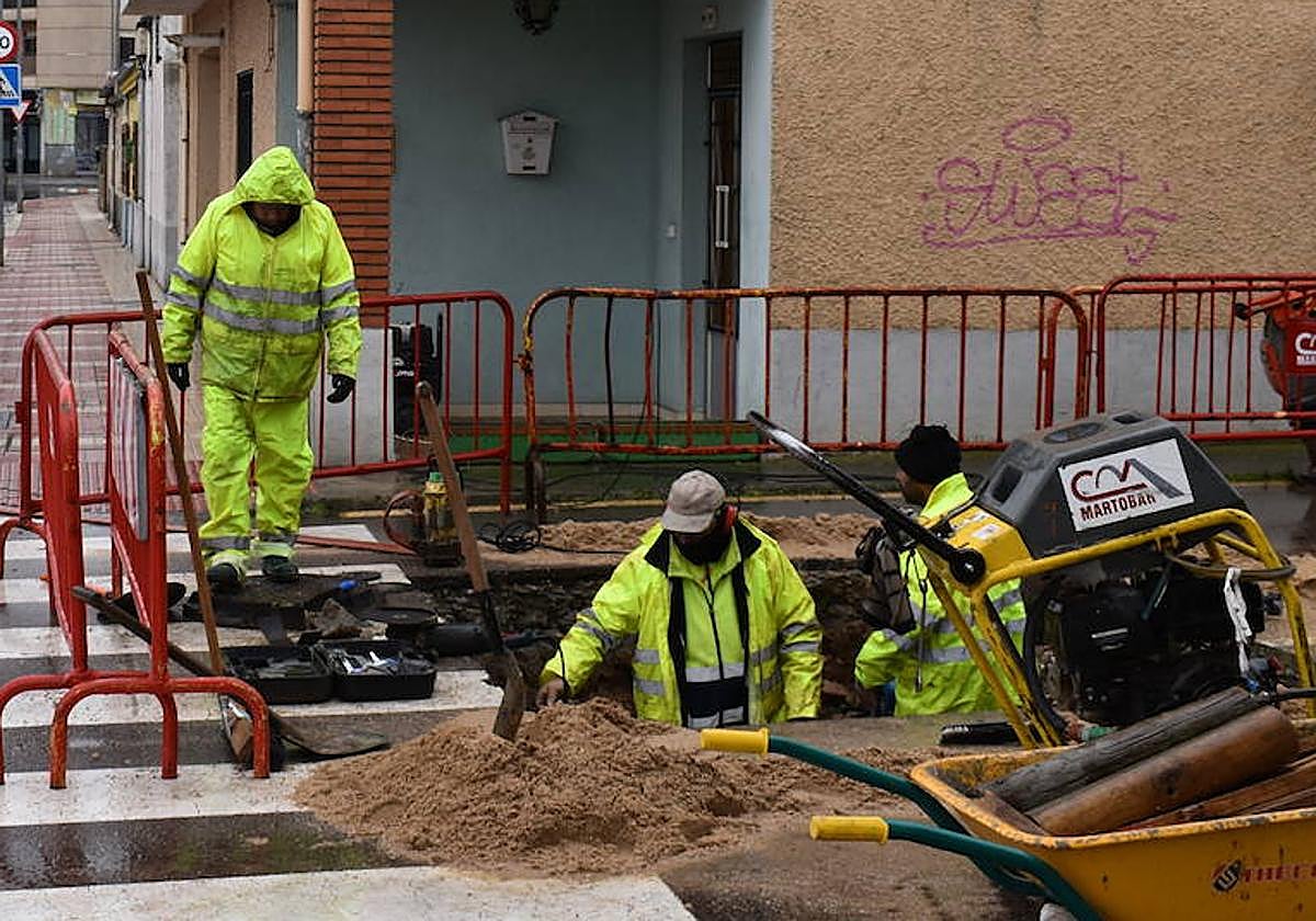 Operarios municipales, trabajando para limpiar el depósito de agua en una calle de Salamanca.