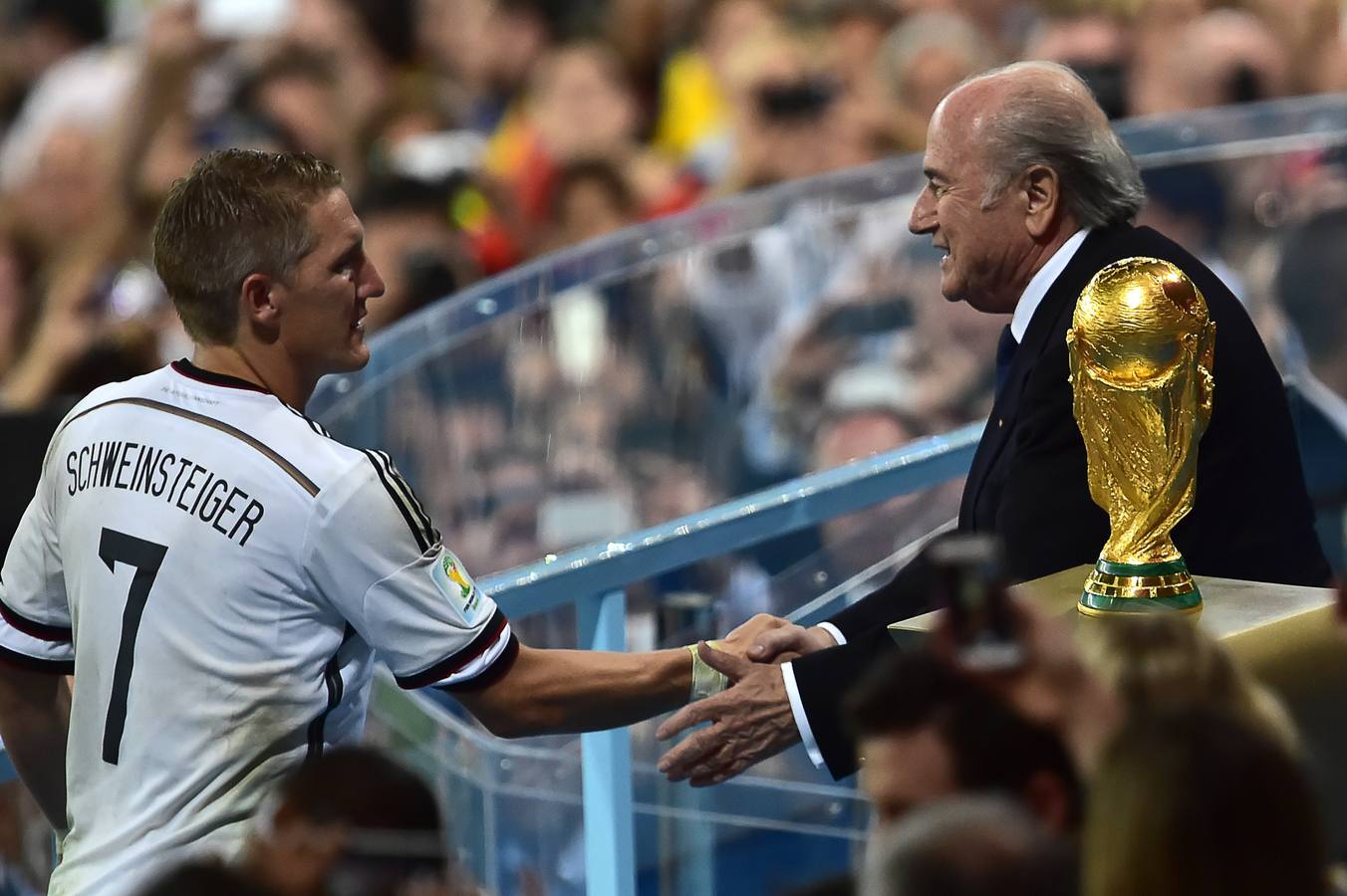 Schweinsteiger (d) da la mano al presidente de la FIFA, Joseph Blatter, junto a la copa del mundo.