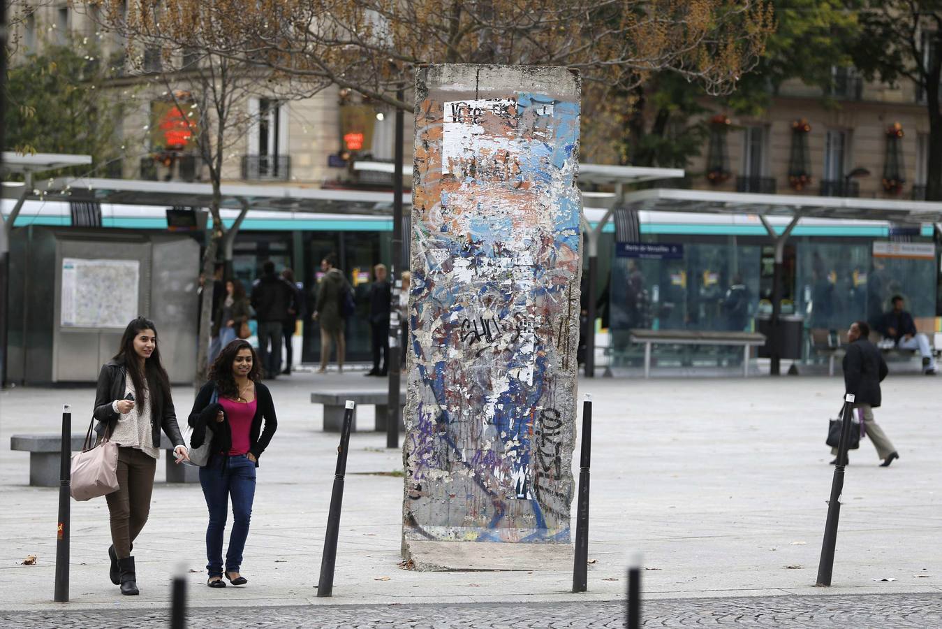 Gente paseando cerca del trozo del Muro que hay en la Puerta de Versalles, en París.