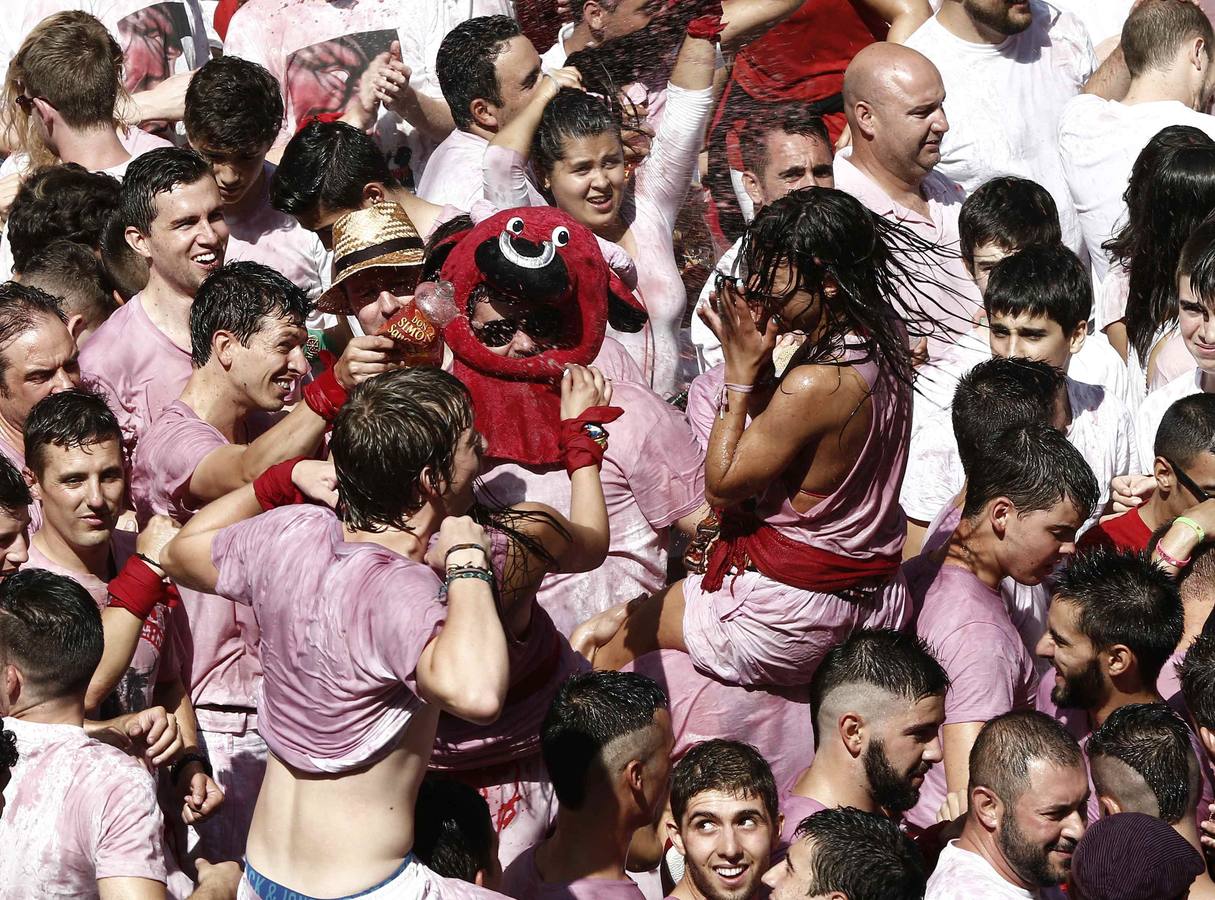 El vino protagoniza la celebración del chupinazo al ser lanzado entre los jóvenes cambiando el color de sus camisetas blancas típicas de Sanfermines.