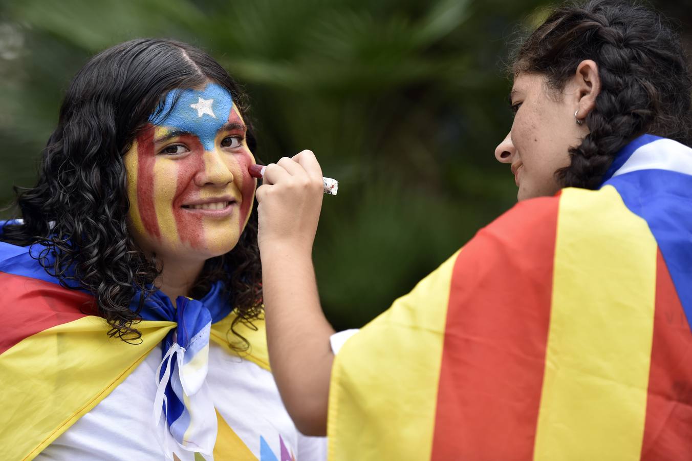 Caras pintadas. Dos jóvenes maquillan sus caras con los colores de la bandera estelada, antes de la manifestación para celebrar la Diada.