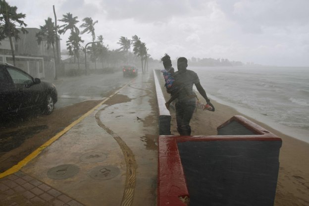 Un hombre atraviesa una zona costera de San Juan con una niña en brazos cuando 'María' comenzaba a llegar a la capital. :: HECTOR RETAMAL / afp
