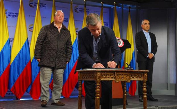 Santos, en el centro, firmando el decreto.