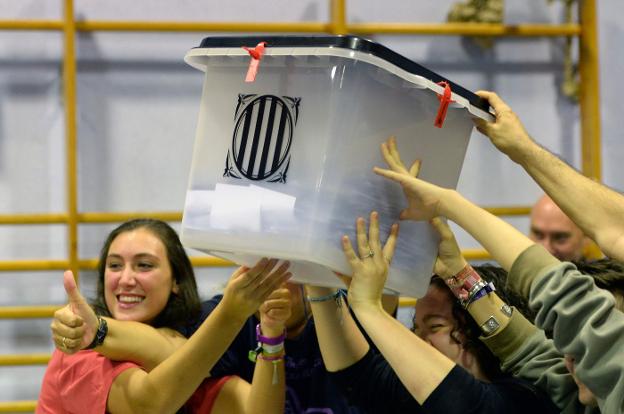 Varios jóvenes sostienen una de las urnas con centenares de votos en su interior al cierre de la jornada electoral en Cataluña. :: josep lago / afp
