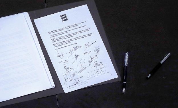 El presidente de la Generalitat, Carles Puigdemont, firma el documento. Abajo, el contenido del texto. :: martín benet / reuters