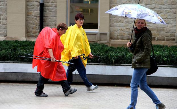 Caminantes y peatones protegidos de la lluvia. 