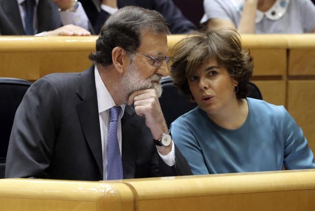 El presidente del Gobierno conversa con la vicepresidenta, Soraya Sáenz de Santamaría, el viernes al inicio del pleno extraordinario del Senado. :: j. j. guillén / efe