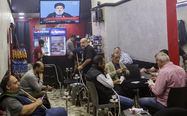 Unos hombres fuman y juegan a las cartas mientras escuchan en un bar de Beirut al líder de Hizbolá Hassan Nasrallah. :: N. M. / efe