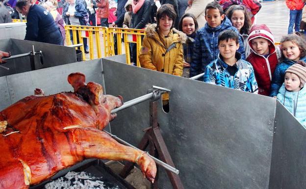 Unos niños observan el proceso de asado de un lechón. 