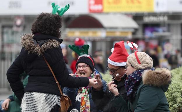 Turista ataviados con gorros navideños reponen fuerzas en la Puerta del Sol de Madrid. 