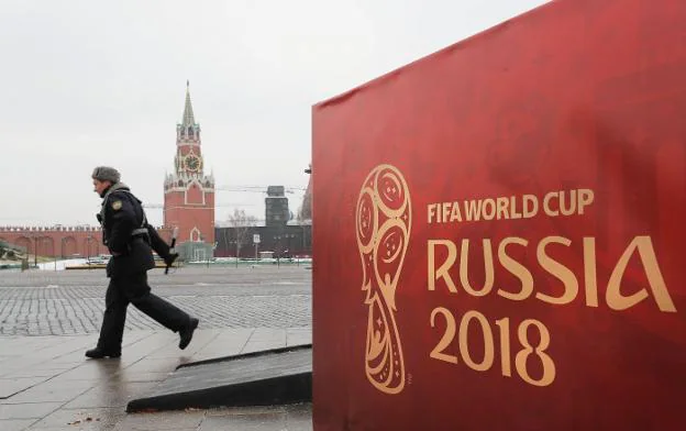 Un oficial ruso pasa junto a un cartel de la Copa del Mundo frente al palacio  del Kremlin. :: YURI KOCHETKOV / Efe