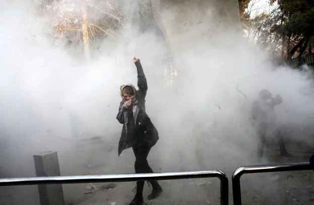 Una estudiante avanza entre gases lacrimógenos en las protestas contra el Gobierno en la Universidad de Teherán. :: efe
