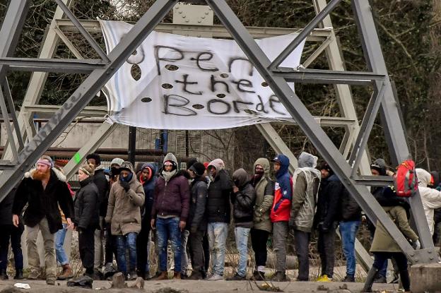 Un grupo de migrantes hace cola para recoger la comida distribuida por las ONG, en Calais. :: F. H / afp