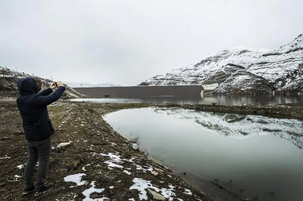 Un hombre saca una foto a la pared de la presa de Soto-Terroba durante los últimos días de episodios de nieve en la zona. :: justo rodríguez