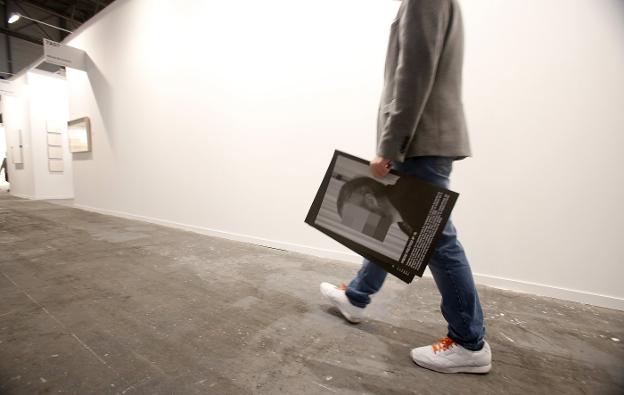 Un hombre camina frente a la pared donde estaba instalada la obra de Sierra con algunos de los retratos censurados. :: alberto ferreras