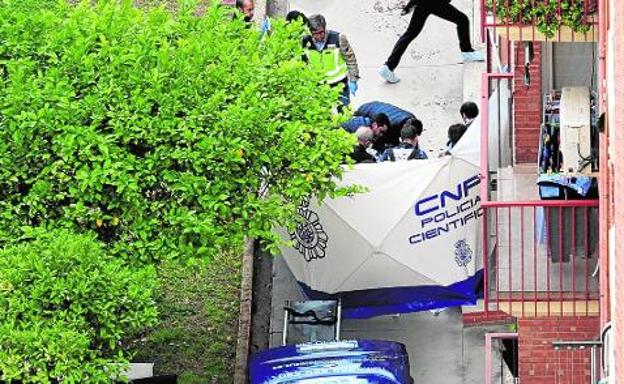 Investigadores de la Policía Nacional realizan pesquisas junto al cadáver de la mujer, ayer, en el jardín comunitario del inmueble.