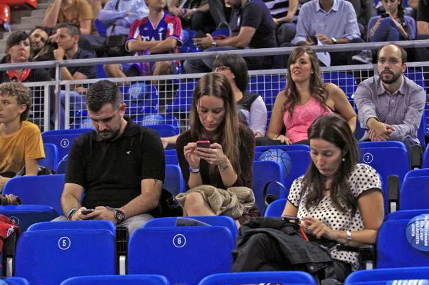 Varias personas usan su
teléfono móvil en un partido
de baloncesto. :: j. andrade