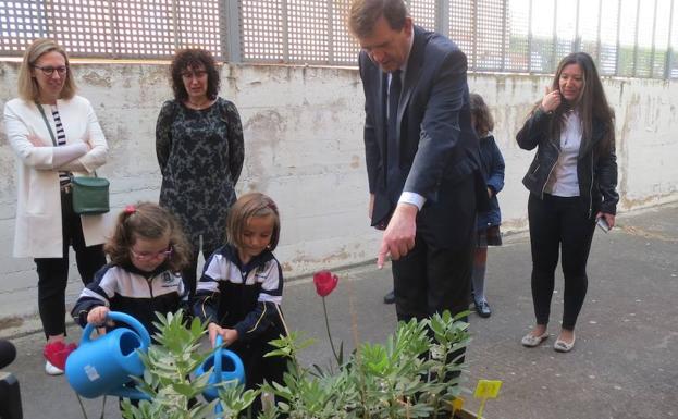 Dos niñas riegan unas plantas en el patido del colegio.