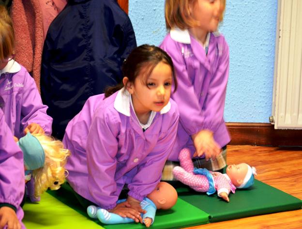 Una niña, practicando el masaje cardiaco con una muñeca. :: i.á. 