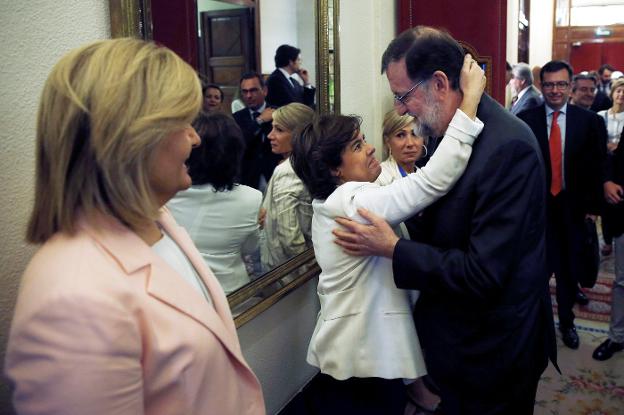 Soraya Sáenz de Santamaría y Mariano Rajoy, ante la mirada de Fátima Báñez, en el pasillo del Congreso después de la moción de censura. :: diego crespo / efe