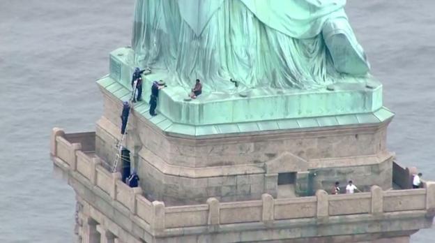 Los agentes intentan convencer a Okoumou para que desista de su protesta y baje de la Estatua de la Libertad, en Nueva York. :: afp
