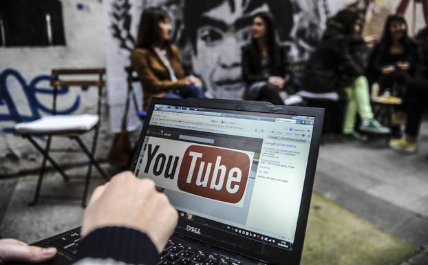 Una persona mostrando un ordenador con el logotipo de Youtube. 