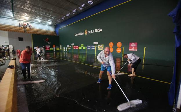 Operarios afanándose en la retirada del agua de la cancha del Adarraga. 