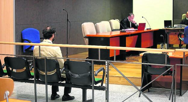 El acusado J.M.M.S. observa desde el banquillo la sala de vistas, con su abogado al fondo. ::  jordi alemany