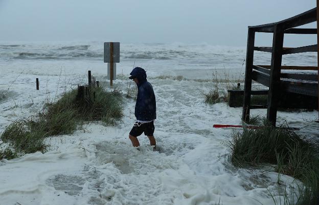 Un joven camina por una playa inundada de Panama City, en Florida, cuando comenzaban a sentirse los primeros vientos de 'Michael'. ::  Joe Raedle / AFP