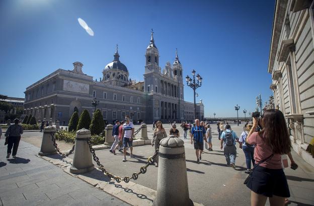 Varios turistas pasean junto a la catedral de la Almudena y el Palacio Real, en el centro de Madrid. :: alberto ferreras