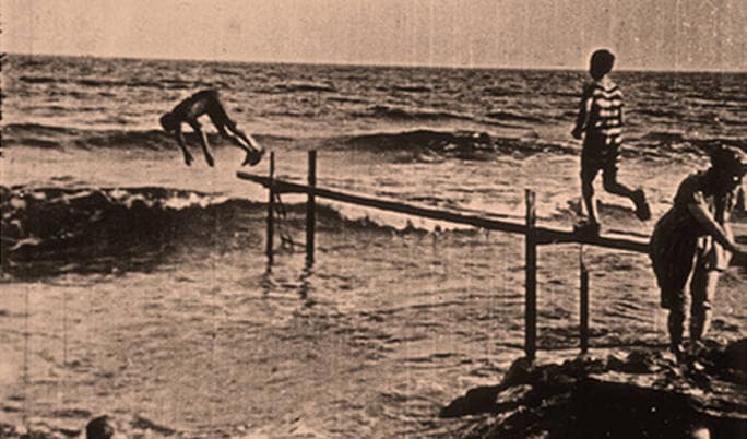 En la playa. «Los niños saltan sobre las olas varias veces desde un trampolín». 