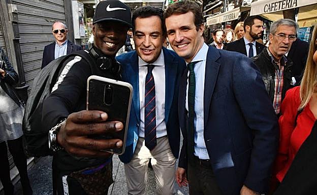 El presidente del Partido Popular, Pablo Casado, junto al candidato a la Presidencia de la Junta de Andalucía para las próximas elecciones autonómicas, Juanma Moreno, se prestan a hacerse un selfi con un joven mientras pasean por el centro de Almería.