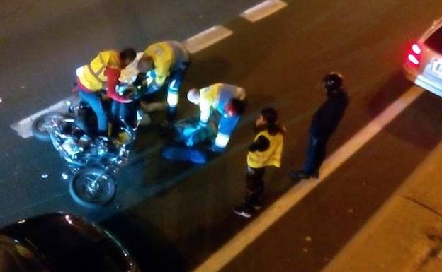 Las asistencias médicas auxilian al motociclista tendido en la carretera.